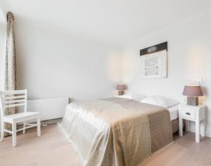 a white bedroom with a bed and a chair at Viktoria 4 you - Whg. 05 in Westerland (Sylt)
