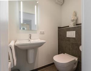 ein Badezimmer mit Waschbecken, Toilette und Spiegel in der Unterkunft Viktoria 4 you - Whg. 04 in Westerland + 9 Fotos