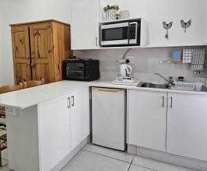 a white kitchen with a sink and a microwave at Flamebreeze Corner @ Supertubes Jeffreys Bay in Jeffreys Bay