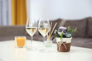 three wine glasses and a vase with flowers on a table at Ninkovic - Raj in Vrnjci