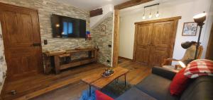 a living room with a couch and a tv on a brick wall at chalet cosy, jacuzzi privé, calme, idéal moto rando vélo in Bellecombe +48 photos