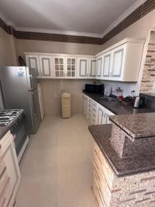 une cuisine avec des armoires blanches et un réfrigérateur dans l'établissement Villa Hana green beach, à El Alamein