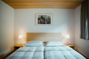 a bedroom with a bed with blue sheets and two lamps at Haus Margreth in Mellau