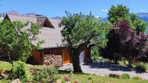 a house with a tree and a table and chairs at Chalet Mounette Ski Sauna Lac Embrun in Puy-Sanières +18 photos