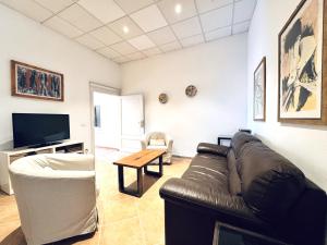 een woonkamer met een leren bank en een tv bij Abbadia Panoramic Terrace in Siena