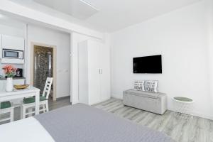 a white room with a bed and a couch and a desk at Studio Apartments Nada in Umag