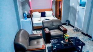a living room with a chair and a bed at MK Hotel in Muisenge