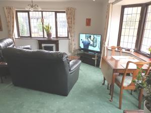 a living room with a couch and a table and a television at The Chantry, North Wing, Cottage in Hemsby
