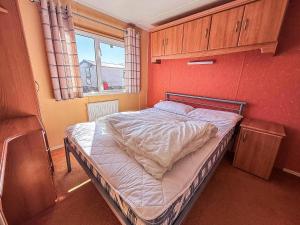 a small bedroom with a bed in a room at Spacious Caravan For Hire With Decking By The Beach In Suffolk Ref 40094Nd in Lowestoft