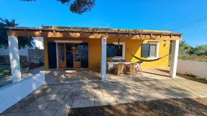 a small yellow house with a table and chairs at Cas Conco in Ciutadella