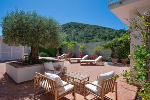 Un patio con sillas y mesas y un árbol. en Dream Villa by the sea, en Porto Santo Stefano
