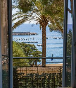 una ventana con vistas a una playa con palmeras en Casa Baia Chiara, air-con, fronte spiaggia, en Cala Gonone