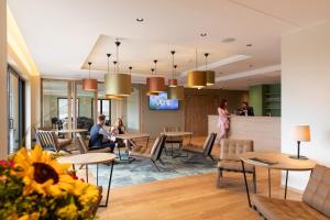 een lobby van een hotel met mensen aan tafel bij Hôtel Terra Vinum in Gueberschwihr