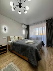 a bedroom with a large bed and a chandelier at Квартира с видом на город in Ustʼ-Kamenogorsk