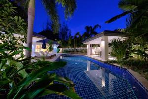 a swimming pool in front of a house at night at BAAN RIM TALAY - Beach Side 2 Bed Pool Villa in Nathon