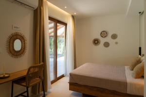 ein Schlafzimmer mit Bett, Schreibtisch und Fenster in der Unterkunft Aluna Boutique Suites in Vasilikos