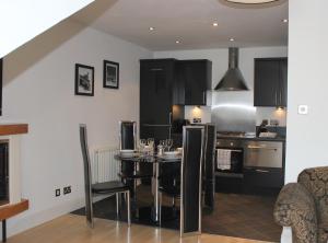 a kitchen with a dining room table and a kitchen with black cabinets at Bego's Apartment in Aberdeen