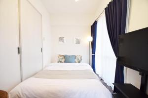 a bedroom with two beds and a flat screen tv at enジョイまーるひろ 401 in Naha