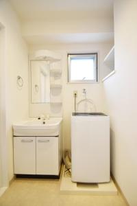 a white bathroom with a sink and a mirror at enジョイまーるひろ 401 in Naha