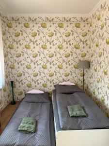 two beds in a room with a wall with flowers at Dió Apartman in Hajdúszoboszló