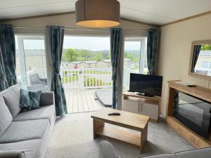 a living room with a couch and a tv at Rural Retreat Chy Kensa a Hot Tub Haven in Grampound