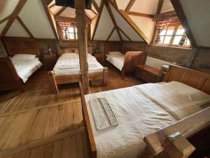 an attic bedroom with two beds and two windows at Brvnara "Duboki Potok" in Vrnjačka Banja
