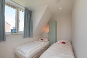 two beds in a room with two windows at Vakantiehuis Westkapelle dichtbij strand in centrum in Westkapelle