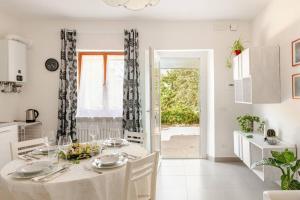a white dining room with a table and a kitchen at I Due Gelsi Appartamento White in Monte San Giusto