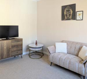 a living room with a couch and a tv and a table at Kirk street apartment in Campbeltown