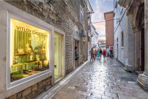 a street with people walking down a street with a store window at DeZign Superior Apartments & Rooms in Zadar