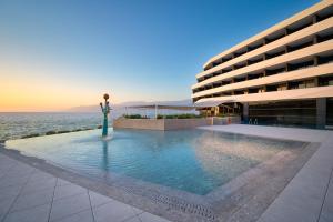 a large building with a swimming pool in front of it at Grand Hotel View in Postira