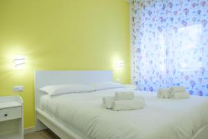 una camera da letto con un letto bianco con asciugamani sopra di RainbHome Colourful Roman Suites a Roma