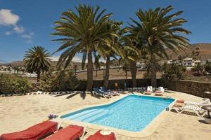 una piscina con sillas y palmeras en una playa en Finca La Crucita - Ye, en Haría