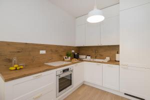 a kitchen with white cabinets and a wooden wall at ShortStayPoland Sokratesa in Warsaw
