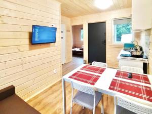 a kitchen with a table and a tv on a wall at Domki Letniskowe SOHO in Bobolin