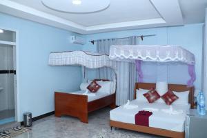two beds in a room with blue walls at MK Hotel in Muisenge