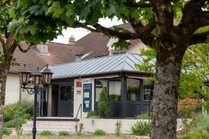 a house with a building with a roof at Kyriad Nuits Saint Georges Dijon Sud in Nuits-Saint-Georges