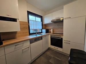 Ferienhaus Nr 96, Kategorie Komfort Plus, Feriendorf Hochbergle, Allgäu في Karlsebene: مطبخ بخزائن بيضاء ونافذة