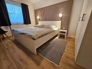 Ferienhaus Nr 96, Kategorie Komfort Plus, Feriendorf Hochbergle, Allgäu في Karlsebene: غرفة نوم مع سرير وأرضية خشبية