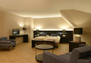 a hotel room with a bed and a couch and chairs at relexa Waldhotel Schatten Stuttgart in Stuttgart