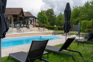 a pool with chairs and umbrellas in the grass at Kyriad Nuits Saint Georges Dijon Sud in Nuits-Saint-Georges