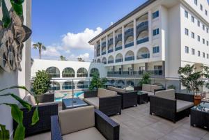 eine Hotelterrasse mit Tischen und Stühlen und ein Pool in der Unterkunft Side Aluna Hotel in Side