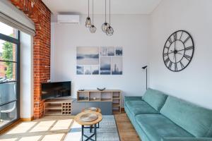 a living room with a green couch and a clock at Shanti barracks apartment #3 by Polo Apartments in Kaunas