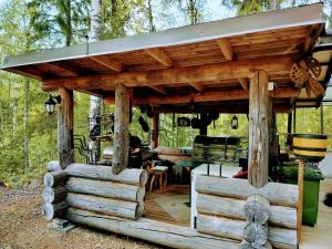 a wooden pavilion in the woods with a table at Kuukkelin Koto in Hämeenlinna