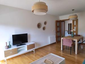 a living room with a tv and a dining room table at Un rincón con vistas a la Ría, playa y parking. in Ribeira