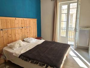 a bedroom with a bed with a blue wall and a window at Appartement duplex in Lectoure
