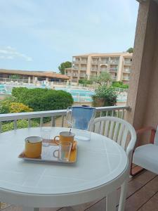 a white table with a tray of drinks on a balcony at Balaruc studio avec piscine parking et climatisation in Balaruc-les-Bains