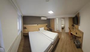 a bedroom with a large white bed and a desk at Hotel Altes Weinhaus in Neustadt an der Weinstraße