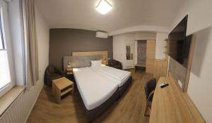 a bedroom with a white bed and a table and a television at Hotel Altes Weinhaus in Neustadt an der Weinstraße