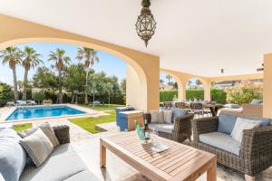eine Terrasse mit Tisch und Stühlen und einem Pool in der Unterkunft Luxury villa next beach Cabo Roig in Orihuela